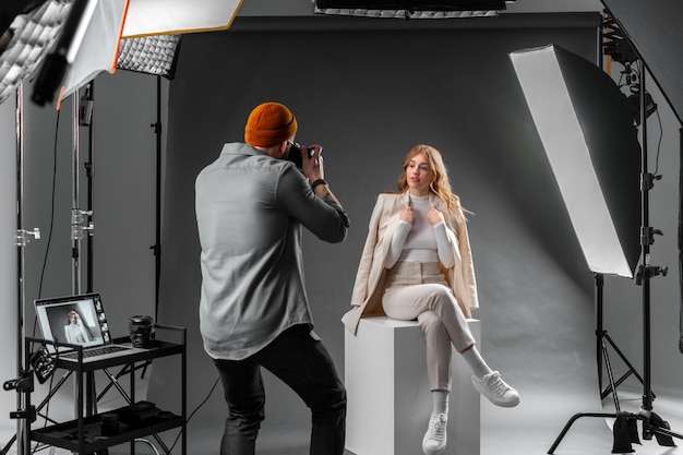 Fotógrafo captura um modelo em um estúdio moderno com equipamento de iluminação profissional e câmera