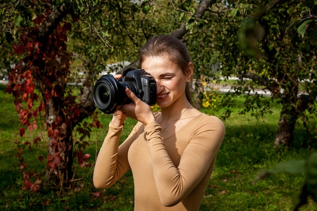 Fotógrafo chica toma una foto con una cámara profesional en el parque