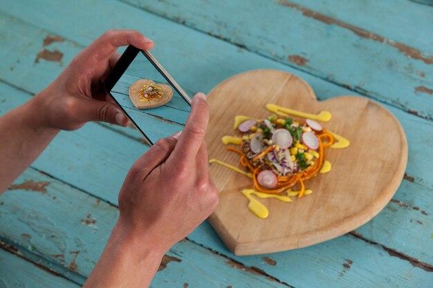 Fotógrafo, clicando em uma imagem de comida usando smartphone