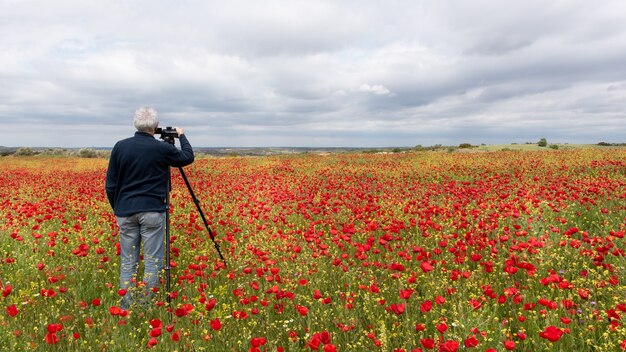 Fotógrafo com tripé tirando foto de um campo de papoulas