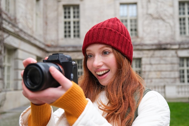 Fotógrafo de garota ruiva tira fotos em câmera profissional ao ar livre captura fotos de estilo de rua lo