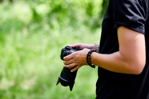 Fotógrafo de homem com uma câmera fotográfica na mão ao ar livre