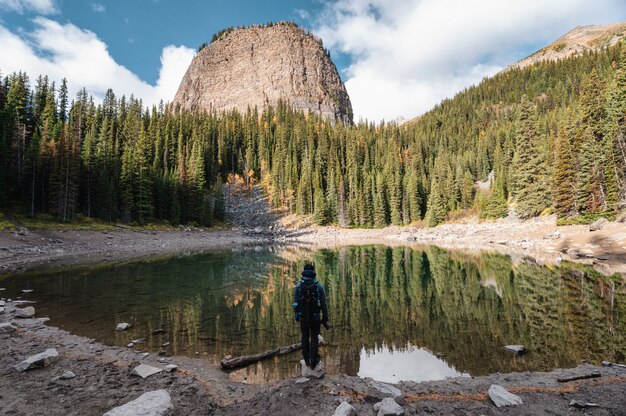 Foto fotógrafo de homem em pé no lago mirror na floresta de outono em lake louise no parque nacional de banff