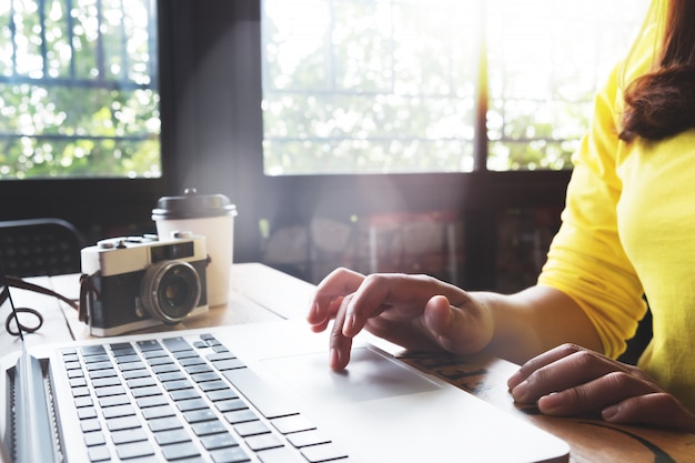 Foto fotógrafo de jovem hippie e viajante usando laptop trabalhando no café