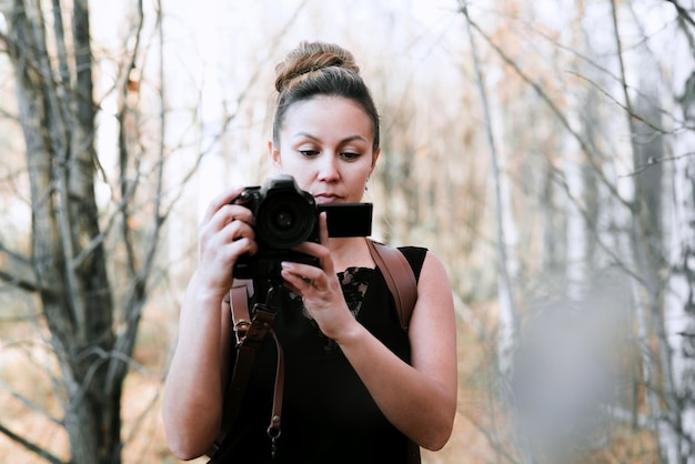 Fotógrafo de menina em um vestido longo preto com descarga em duas câmeras com uma SLR e câmera de filme