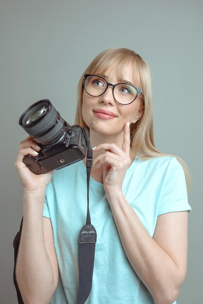 fotógrafo de mulher alegre elegante de óculos e segurando a câmera fotográfica