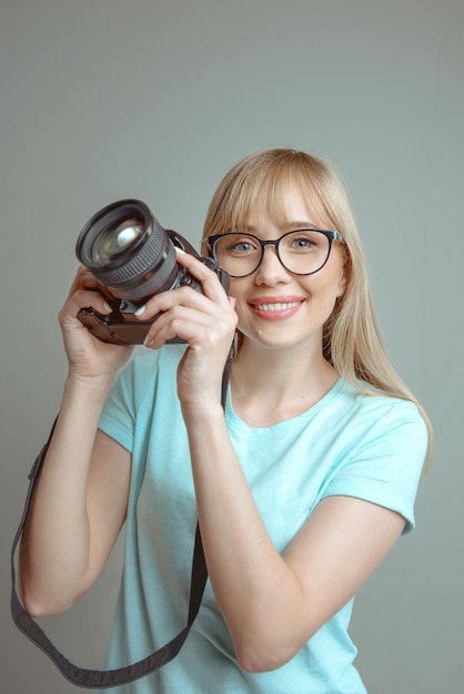 fotógrafo de mulher alegre elegante de óculos e segurando a câmera fotográfica