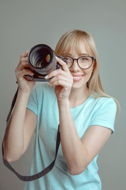 fotógrafo de mulher alegre elegante de óculos e segurando a câmera fotográfica