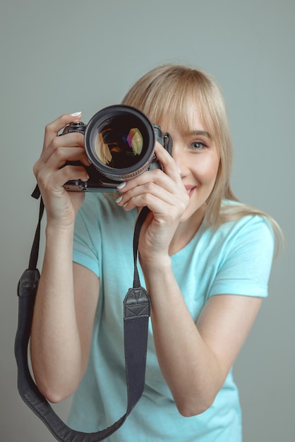 fotógrafo de mulher alegre elegante de óculos e segurando a câmera fotográfica