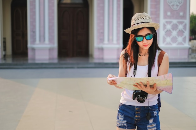 fotógrafo de mulher andando no mercado velho e usando o mapa local.