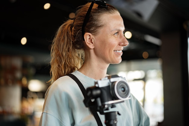 Fotógrafo de mulher com câmera profissional dentro de casa