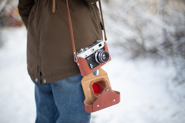 Fotógrafo de mulher com câmera retro em tempo de neve no inverno