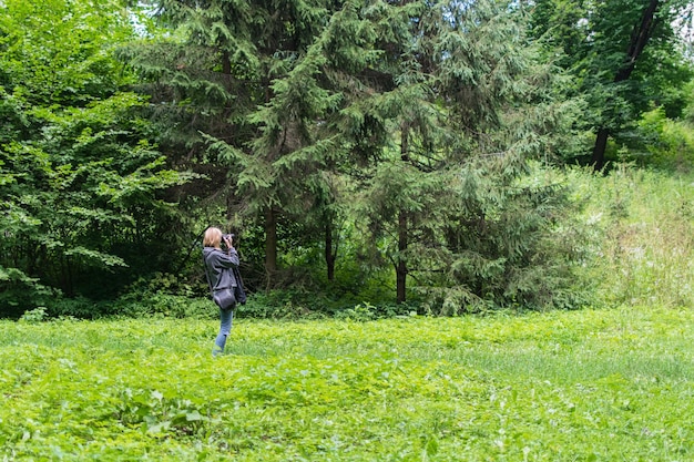 Fotógrafo de mulher tirando foto em uma floresta verde no verão