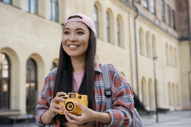 Fotógrafo de turista asiático feliz segurando uma câmera fotográfica e tirando foto