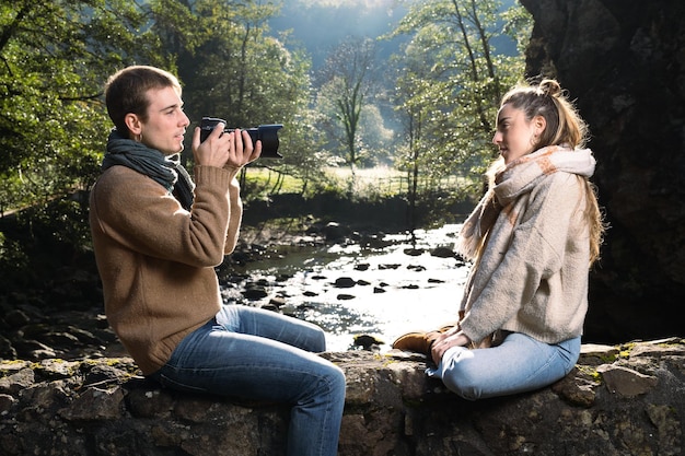 Fotógrafo dirigiendo un modelo en la naturaleza junto a un río.