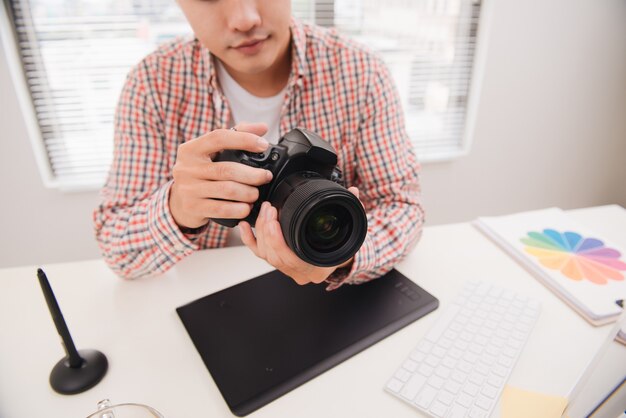 Fotógrafo do sexo masculino sentado em sua mesa, olhando para a câmera