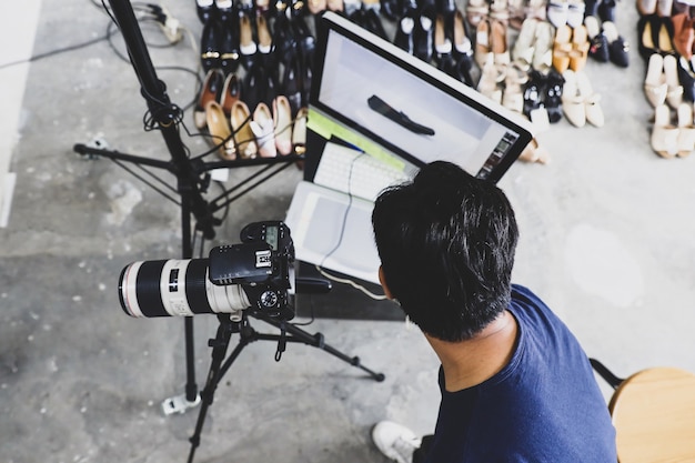 Foto fotógrafo do sexo masculino trabalhando com tripé de câmera de monitor e suporte de luz