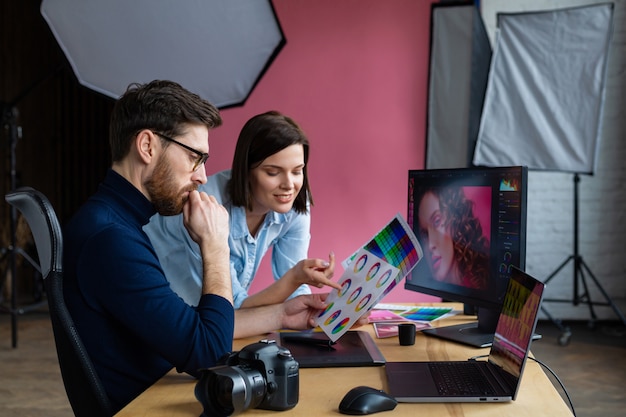 Foto fotógrafo e designer gráfico, trabalhando no escritório com laptop, monitor, tablet de desenho gráfico e paleta de cores.