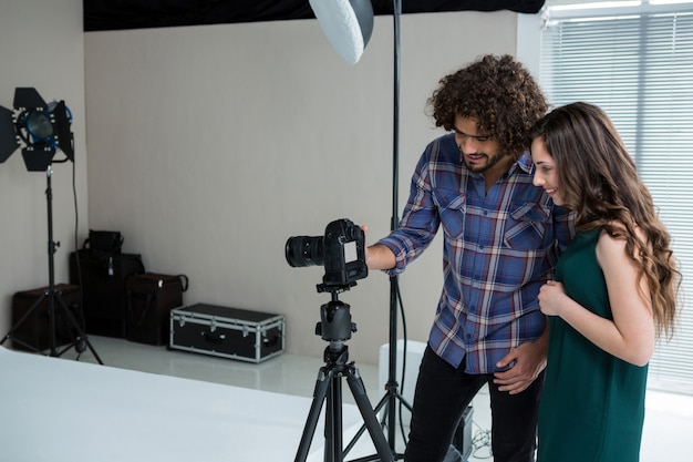 Fotógrafo e modelo feminino revendo fotos capturadas na câmera digital