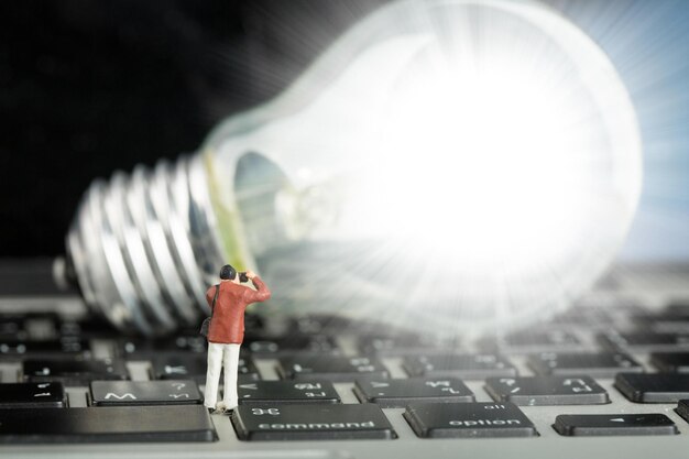 El fotógrafo encontró el concepto de ideas creativas con una bombilla humana en miniatura en un teclado