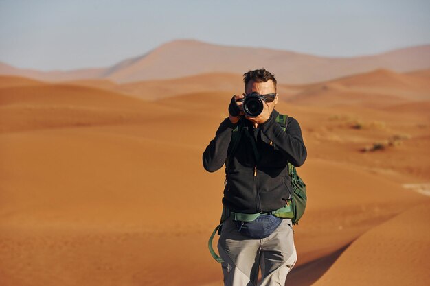 Fotógrafo está trabalhando Turista masculina em roupas casuais está nos desertos da África Namíbia