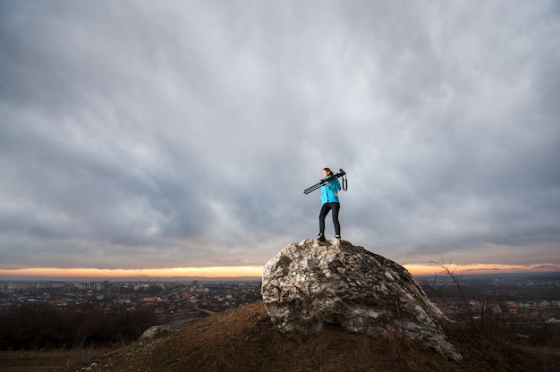 Foto fotógrafo feminino com câmera no tripé na grande rocha