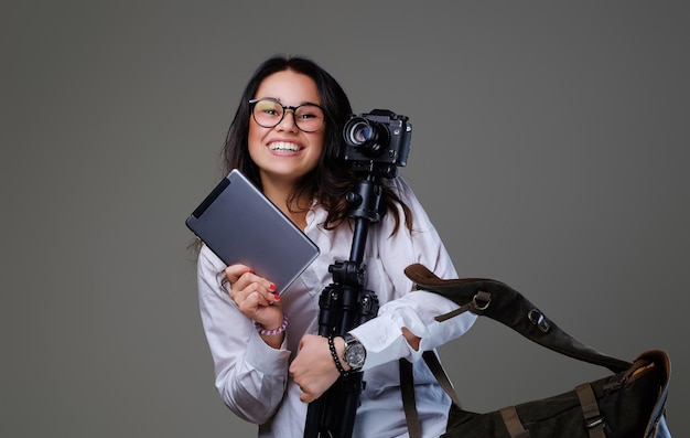 Foto fotógrafo feminino sorridente detém tripé e tablet pc.