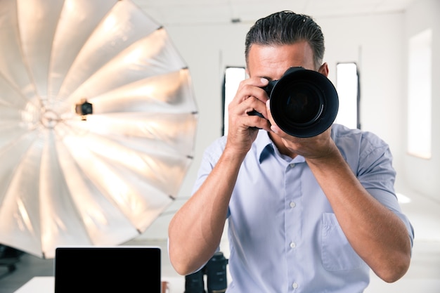 Foto fotógrafo haciendo fotos en cámara en estudio