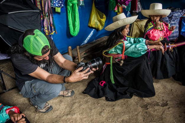 Fotógrafo haciendo retratos de una madre y sus hijas tejiendo en el altiplano peruano