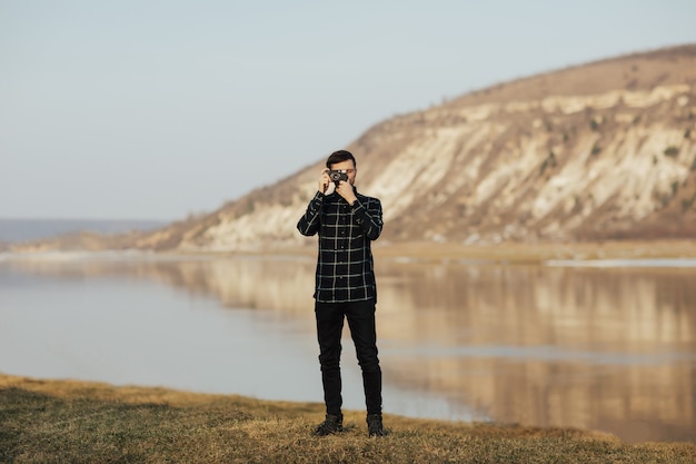Fotógrafo de hombre tomando fotografías con una cámara vintage en una montaña