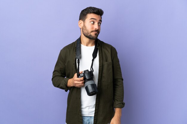 Fotógrafo homem sobre isolado fundo roxo fazendo dúvidas gesto olhando para o lado