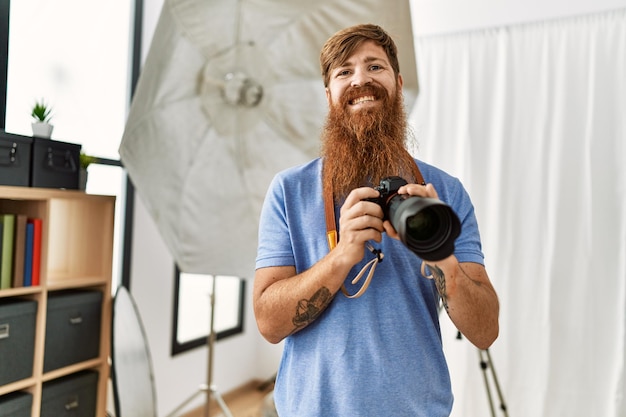 Fotógrafo jovem ruiva usando câmera profissional no estúdio de fotografia