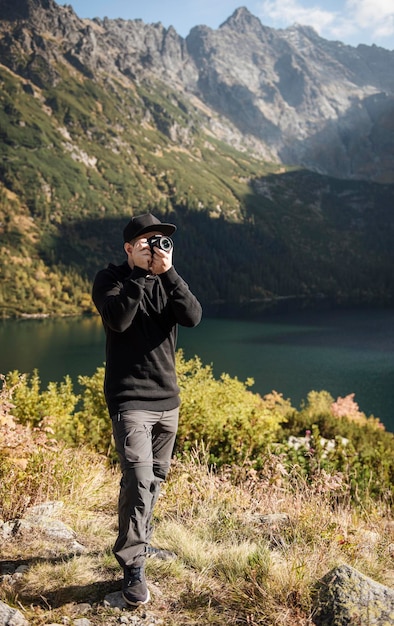 Fotógrafo jovem tirando fotos com câmera digital em uma montanha