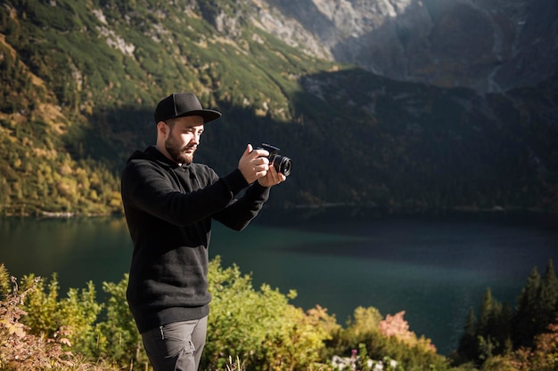 Fotógrafo jovem tirando fotos com câmera digital em uma montanha