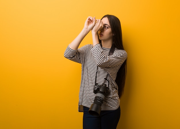 Fotógrafo joven mujer haciendo el gesto de un catalejo