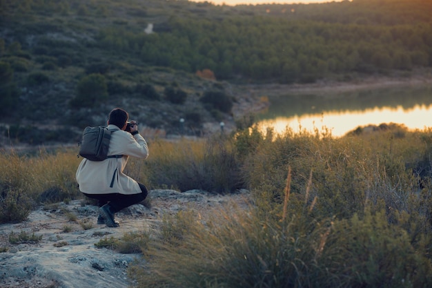 Un fotógrafo latino con una cámara toma fotos en una laguna al atardecer