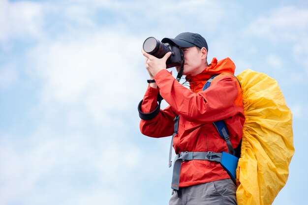 Fotógrafo masculino con cámara y mochila en el cielo nublado