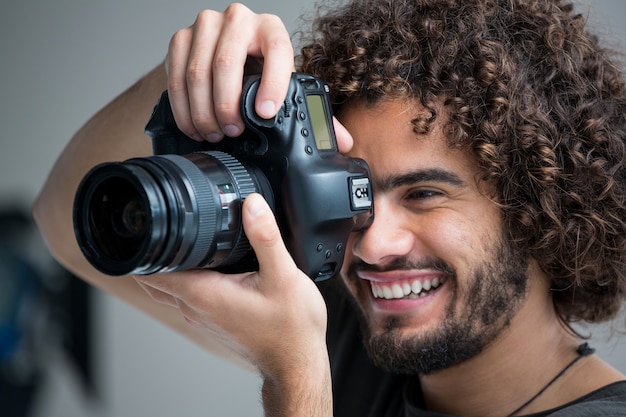 Fotógrafo masculino com câmera digital em estúdio