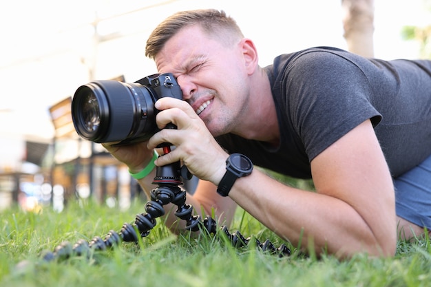 Fotógrafo masculino hace fotos en un trípode mientras está acostado en el suelo fotógrafo de profesión de formación