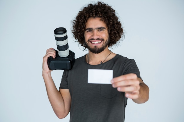 Fotógrafo masculino mostrando tarjeta de visita en estudio