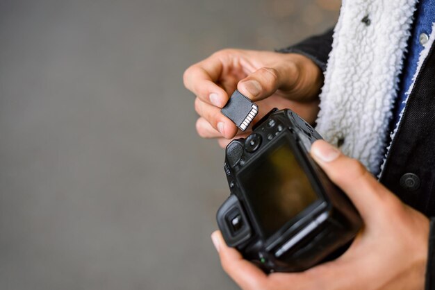 Fotógrafo masculino que inserta la tarjeta de memoria SD en la cámara réflex digital