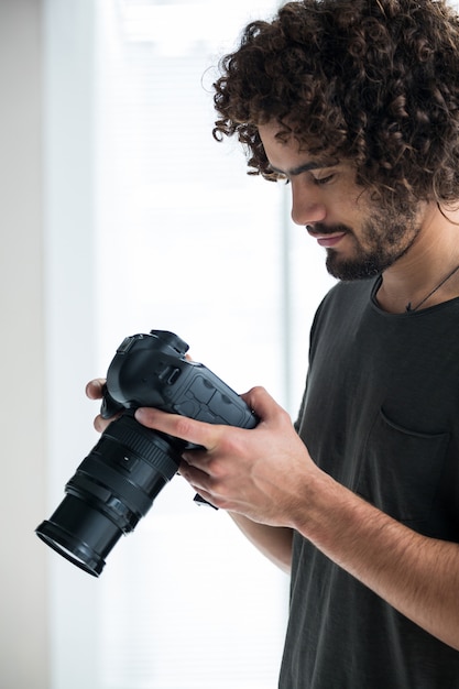 Foto fotógrafo masculino revisando fotos capturadas en su cámara digital