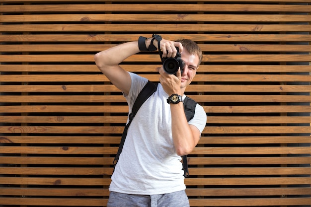 Fotógrafo masculino sem rosto com a câmera digital slr no fundo de madeira