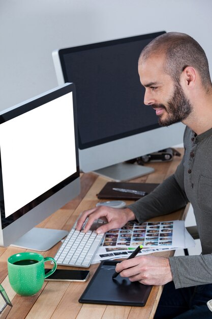 Fotógrafo masculino usando tablet gráfico na mesa