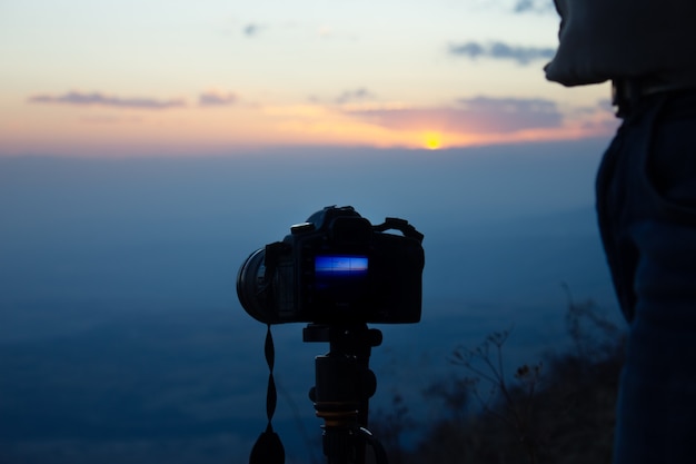 El fotógrafo en la montaña toma una foto al atardecer.