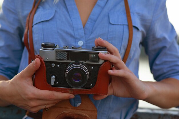 Fotógrafo de mujer hermosa hipster en camisa azul con cámara de película vintage en estuche de cuero marrón