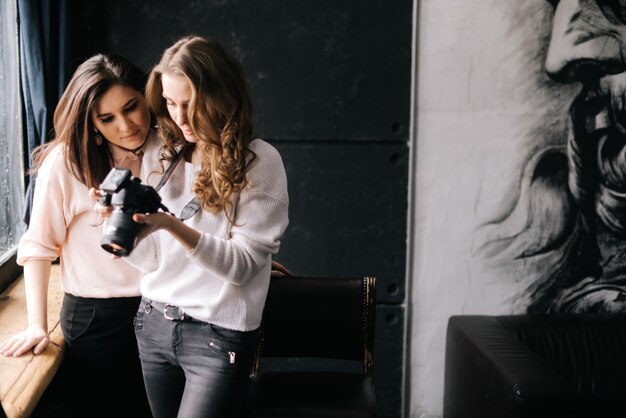 Fotógrafo de mujer hermosa joven que muestra fotos a los clientes en la pantalla de la cámara de fotos en el estudio