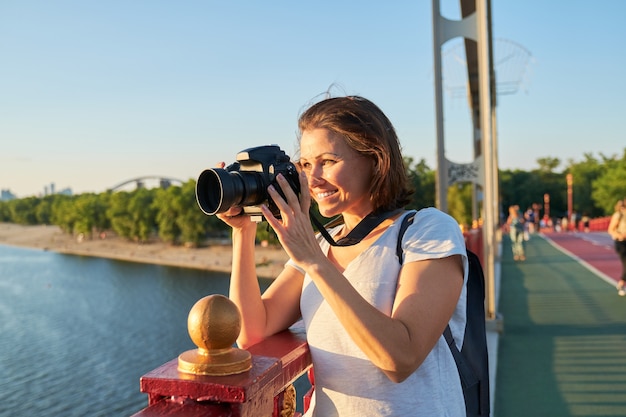 Fotógrafo de mujer madura con cámara tomando fotos