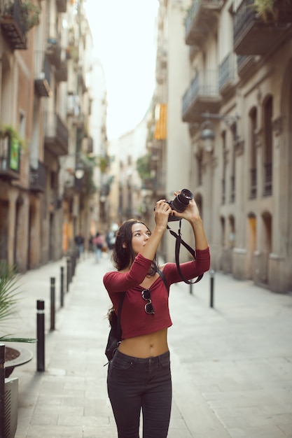 Fotógrafo de mujer turística atractiva tomando imágenes con cámara réflex digital al aire libre en las calles de la ciudad