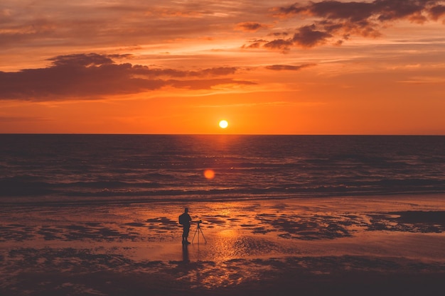 Fotógrafo na praia durante o pôr-do-sol